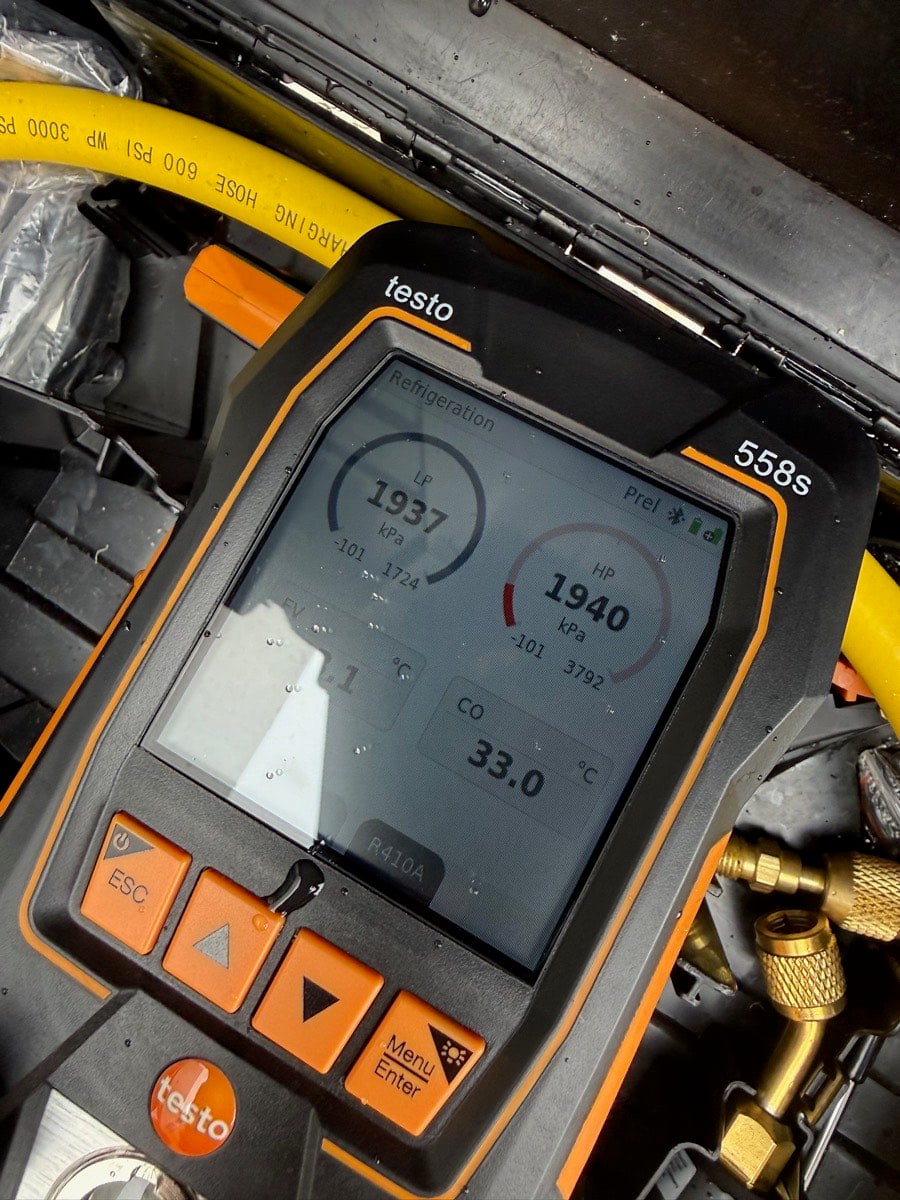Digital manifold gauge checking refrigerant charge and operating pressures during a 40 point maintenance