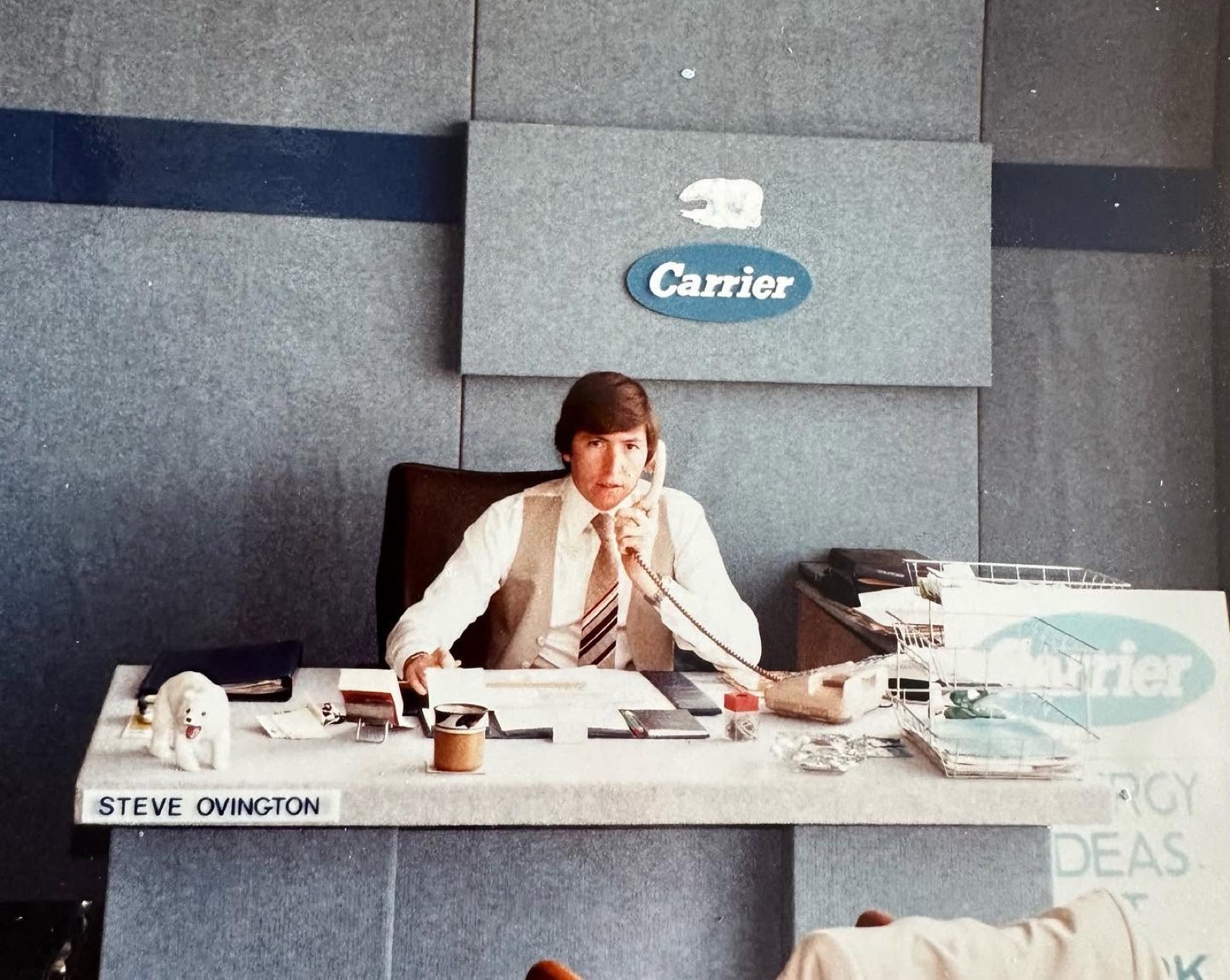 Steven Ovington at his desk under the Carrier sign, early 1980s